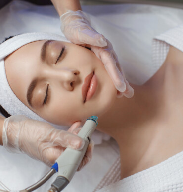 Side view of woman receiving microdermabrasion therapy on forehead at beauty spa. Hydrafacial procedure in Cosmetology clinic.