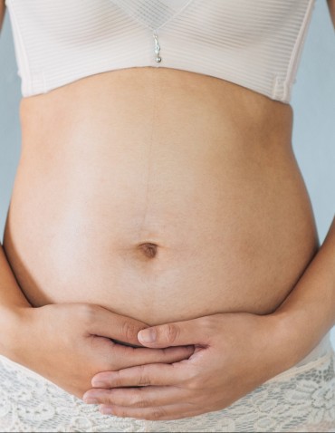 Pregnant woman holds hands on belly