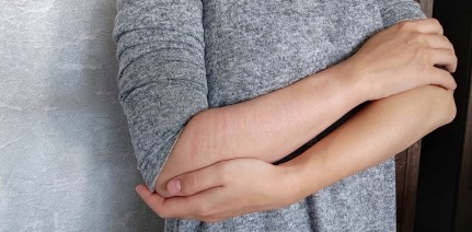 woman with self-harm scars wraps her arms around herself