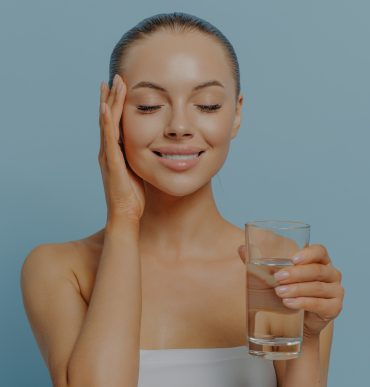young women with hydrated skin holding a glass of water