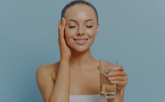 young women with hydrated skin holding a glass of water