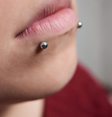 Close-up of a lower lip piercing with a silver ball stud.