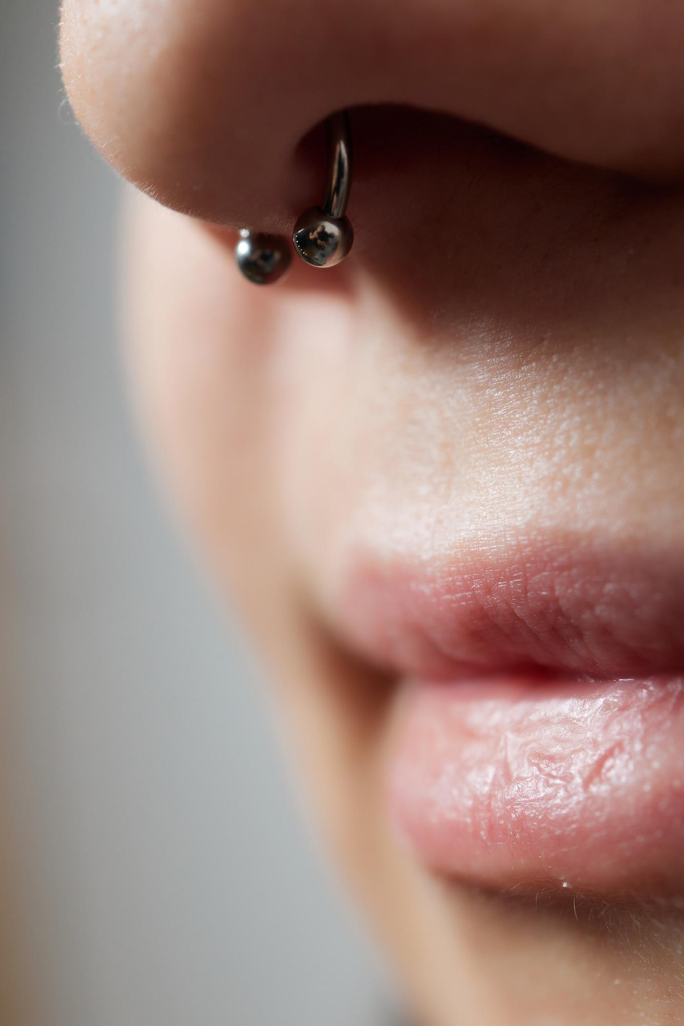 Close-up of a septum piercing with a silver horseshoe ring.